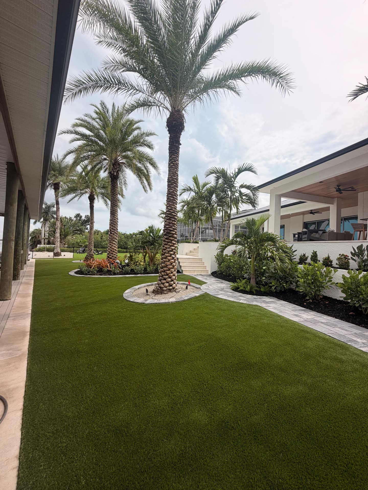 Artificial turf side yard framed by palms and a paver walkway
