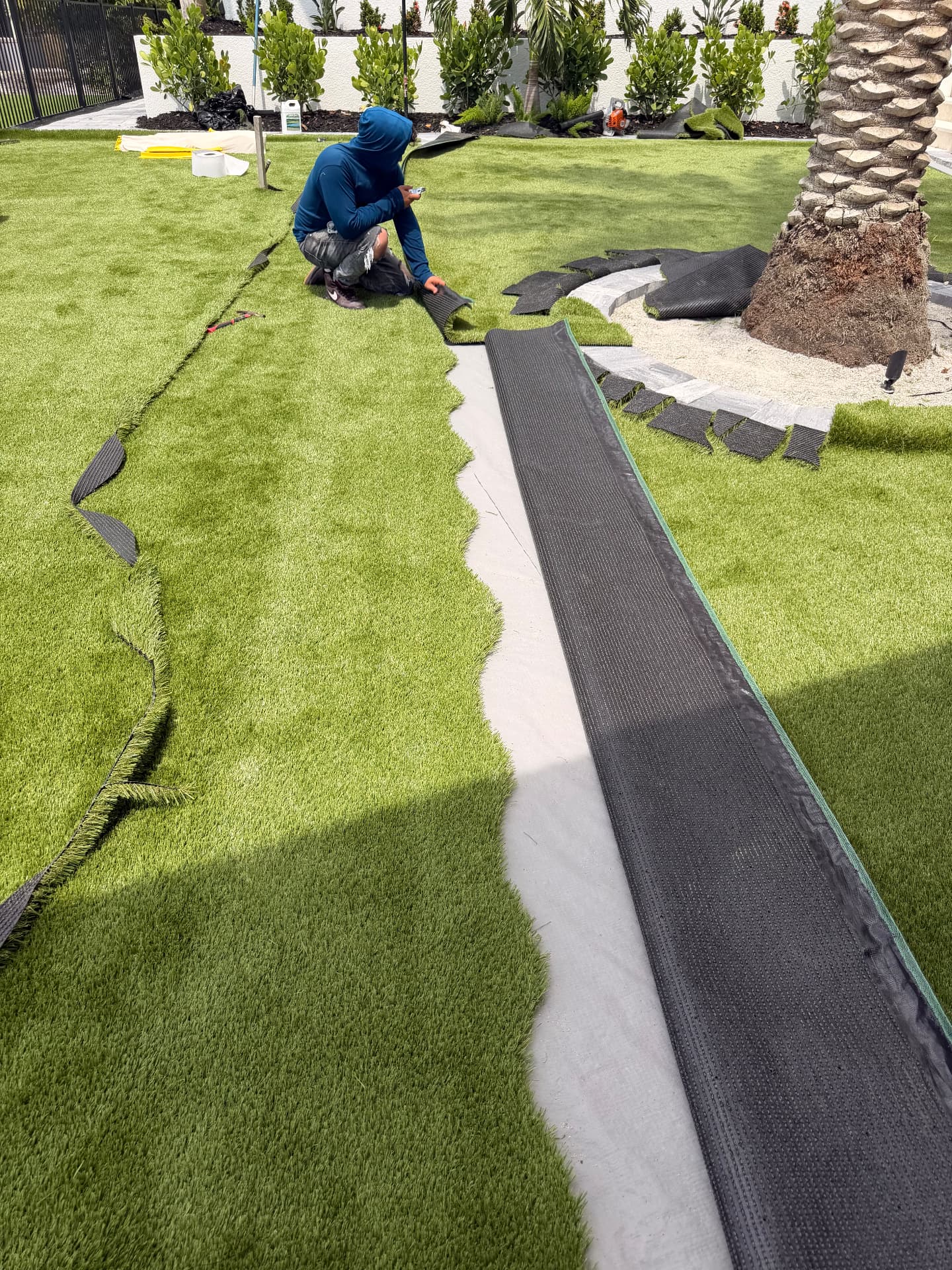 Crew seaming artificial turf during installation around a palm tree
