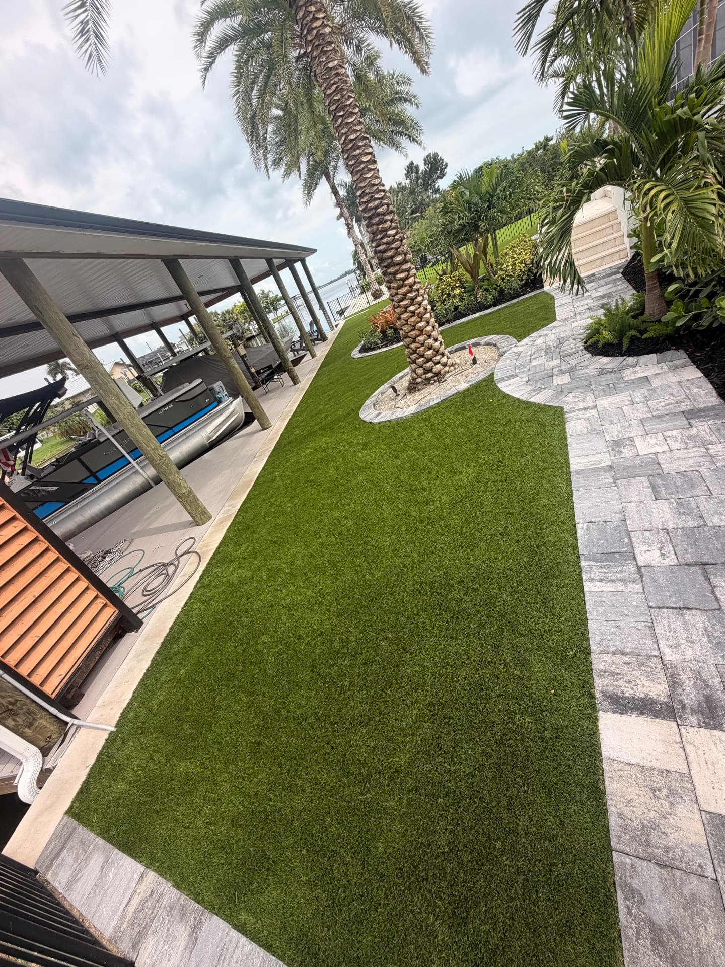 Long strip of artificial turf between paver patio and boat dock